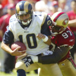 
              FILE - St. Louis Rams quarterback, Marc Bulger, left, is sacked by San Francisco 49ers Bryant Young during an NFL football game on Sept. 11, 2005 in San Francisco. Young's ability to inspire — both through his play and through his response to unimaginable setbacks on and off the field — finally earned him admission to the Pro Football Hall of Fame this summer, nearly 15 years after his last game. (AP Photo/George Nikitin, File)
            