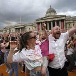 
              FILE - England supporters celebrate after Chloe Kelly scored their second goal as they gather in the fan zone in Trafalgar Square to watch on a big screen the final of the Women's Euro 2022 soccer match between England and Germany being played at Wembley stadium in London, Sunday, July 31, 2022. (AP Photo/Frank Augstein, File)
            