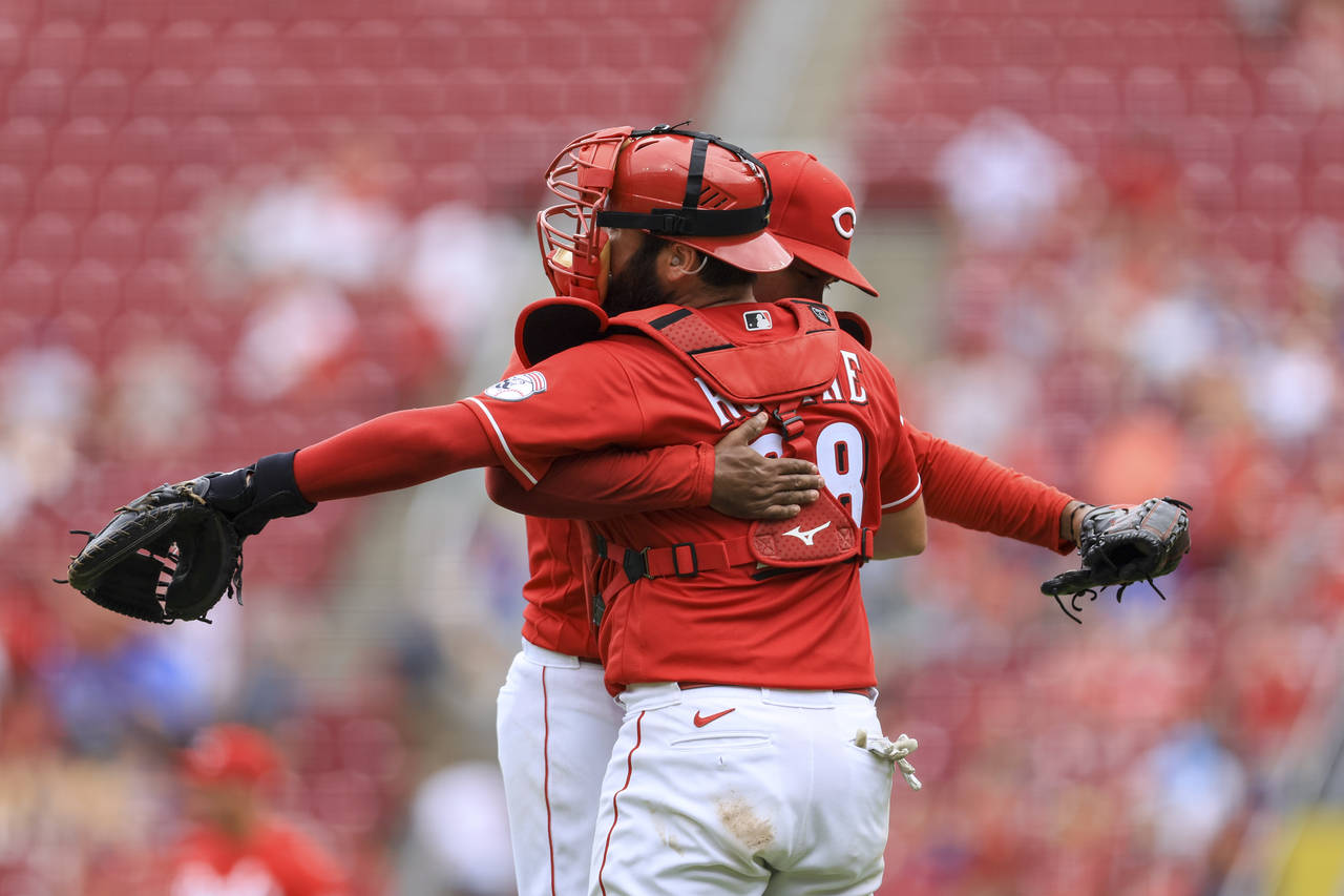Cincinnati Reds' Alexis Diaz, right, hugs Austin Romine after the final out of a baseball game agai...