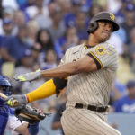 
              San Diego Padres' Juan Soto, right, hits a single as Los Angeles Dodgers catcher Will Smith watches during the first inning of a baseball game Friday, Aug. 5, 2022, in Los Angeles. (AP Photo/Mark J. Terrill)
            