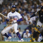 
              Los Angeles Dodgers' Mookie Betts (50) runs to first while Milwaukee Brewers catcher Omar Narvaez (10) chases a wild pitch during the fourth inning of a baseball game in Los Angeles, Tuesday, Aug. 23, 2022. (AP Photo/Ashley Landis)
            