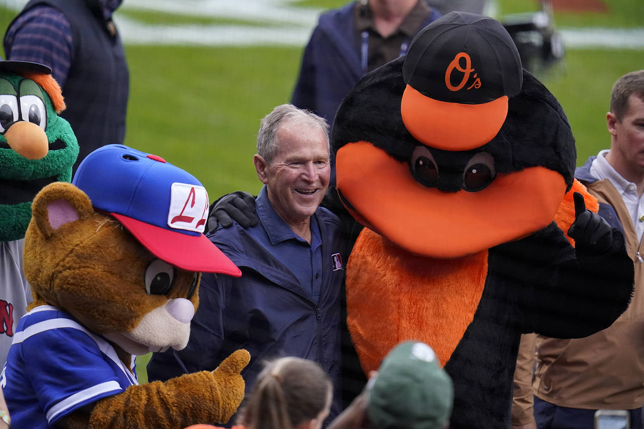 Former President George W. Bush, center, is surrounded by mascots during pre-game festivities befor...