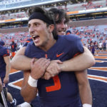 
              Illinois quarterback Tommy DeVito is hugged by a teammate after their win over Wyoming in an NCAA college football game Saturday, Aug. 27, 2022, in Champaign, Ill. (AP Photo/Charles Rex Arbogast)
            