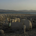 
              Amalie Garcia, 54, stands next to The Dolmen of Guadalperal, a megalithic monument that emerged due to drought at the Valdecanas reservoir in El Gordo, western Spain, Saturday, Aug. 13, 2022. In the wake of three heatwaves and little rain in sight, Spain's reservoirs are getting emptier by the week, and not just in traditionally more arid southern part of the country. Spain's drought began early in the year after the country suffered its second driest winter in more than 60 years, according to the government. (AP Photo/Manu Fernandez)
            