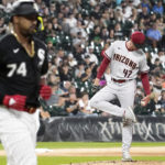 
              Arizona Diamondbacks starting pitcher Tommy Henry, right, checks his shoes as Chicago White Sox's Eloy Jimenez walks to first during the second inning of a baseball game in Chicago, Friday, Aug. 26, 2022. (AP Photo/Nam Y. Huh)
            