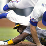 
              Oakland Athletics' Tony Kemp holds on to third base as Texas Rangers shortstop Corey Seager falls over him while grabbing the throw during the first inning of a baseball game in Arlington, Texas, Tuesday, Aug. 16, 2022. Kemp advanced to third on a single by Seth Brown that also scored Cal Stevenson. (AP Photo/Tony Gutierrez)
            