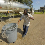 
              Santonia Matthews, a custodian at Forest Hill High School in Jackson, Miss., hauls away a trash can filled with water from a tanker in the school's parking lot, Wednesday, Aug. 31, 2022. The tanker is one of two placed strategically in the city to provide residents non-potable water. The recent flood worsened Jackson's longstanding water system problems and the state Health Department has had Mississippi's capital city under a boil-water notice since late July. (AP Photo/Rogelio V. Solis)
            