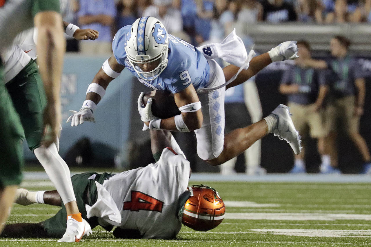 North Carolina's Cam'Ron Kelly (9) is upended by Florida A&M's Kym'Mani King (4) as he runs the bal...