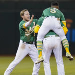
              Oakland Athletics' Nick Allen, left, and Tony Kemp (5) celebrate with Chad Pinder who grounded into a force out but reached first base safely on a throwing error by New York Yankees second baseman DJ LeMahieu, driving in the winning run in the 11th inning of a baseball game in Oakland, Calif., Saturday, Aug. 27, 2022. (AP Photo/Godofredo A. Vásquez)
            