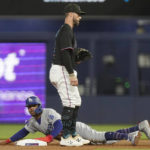
              Los Angeles Dodgers' Mookie Betts, bottom, steals second base as Miami Marlins third baseman Jon Berti, top, is late with the tag during the first inning of a baseball game, Friday, Aug. 26, 2022, in Miami. (AP Photo/Marta Lavandier)
            