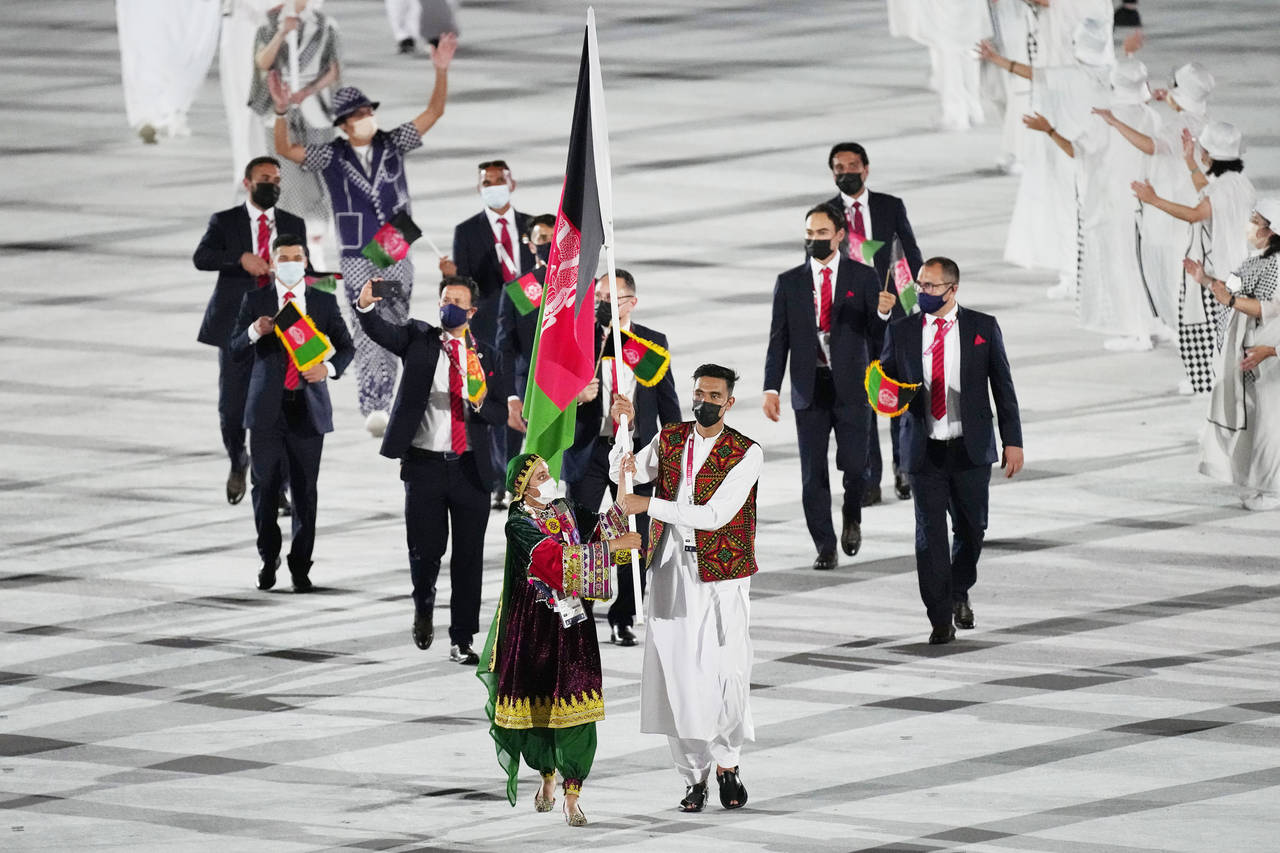 FILE - Kimia Yousofi, front left, and Farzad Mansouri, of Afghanistan, carry their country's flag d...