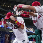 
              Philadelphia Phillies' Nick Maton, left, is doused with water by Bryson Stott, center, and Rhys Hoskins after hitting a game-winning RBI-single against Cincinnati Reds pitcher Alexis Diaz during the ninth inning of a baseball game, Tuesday, Aug. 23, 2022, in Philadelphia. (AP Photo/Matt Slocum)
            