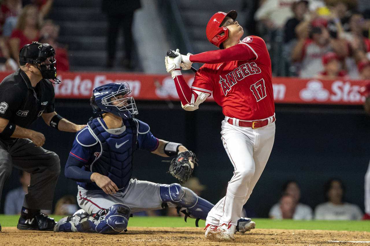 Los Angeles Angels designated hitter Shohei Ohtani, right, hits a pop fly for an out to Minnesota T...