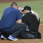 
              MLB home plate umpire Jim Reynolds is assisted on the field after he was hit by a pitch in the eighth inning of a baseball game against the Miami Marlins, Tuesday, Aug. 30, 2022, in Miami. (AP Photo/Marta Lavandier)
            