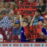 
              Two young fans hold signs in support of Reds' Joey Votto during the ninth inning of a baseball game between the Miami Marlins and the Cincinnati Reds in Cincinnati, Tuesday, July 26, 2022. The Marlins won 2-1. (AP Photo/Aaron Doster)
            