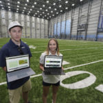 
              Peter Engler, left, a football research assistant, and Becca Erenbaum, a senior football research analyst, hold laptop computers as they pose for a photo on Aug. 3, 2022 at the Seattle Seahawks' NFL football indoor training facility in Renton, Wash. Their job is to make sense of numbers and systems. They run code and develop programs and live in a world of language that if interpreted and translated correctly can be a differentiator between success and failure. (AP Photo/Ted S. Warren)
            