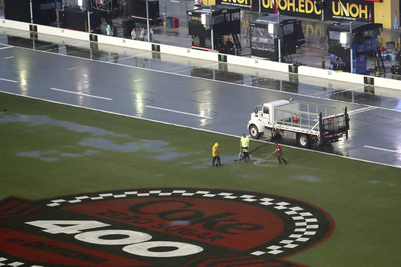 Track workers attempt to clear some of the water off of the infield grass as rain falls before a NA...