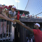 
              Cincinnati Reds' Hunter Greene signs items for fans before a baseball game against the Chicago Cubs at the Field of Dreams movie site, Thursday, Aug. 11, 2022, in Dyersville, Iowa. (AP Photo/Charlie Neibergall)
            