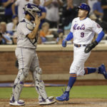 
              New York Mets' Brandon Nimmo (9) scores a run past Colorado Rockies catcher Elias Diaz during the seventh inning of a baseball game on Saturday, Aug. 27, 2022, in New York. (AP Photo/Adam Hunger)
            