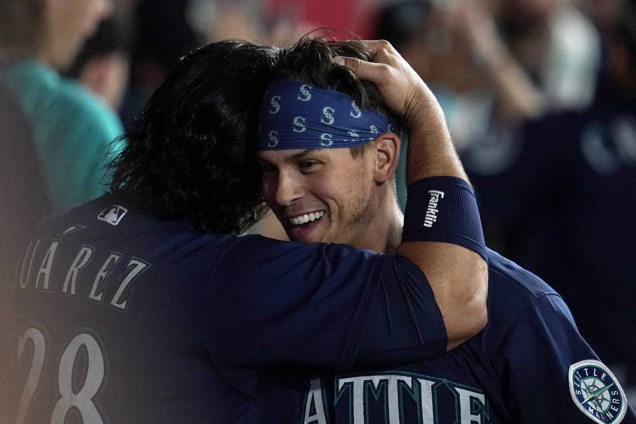 Seattle Mariners' Sam Haggerty, right, is hugged by Eugenio Suarez after Haggerty scored on a singl...