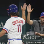 
              Texas Rangers' Charlie Culberson (11) gets a high five from manager Chris Woodward after scored on a sacrifice bunt by teammate Bubba Thompson during the fourth inning of a baseball game against the Seattle Mariners in Arlington, Texas, Saturday, Aug. 13, 2022. (AP Photo/LM Otero)
            
