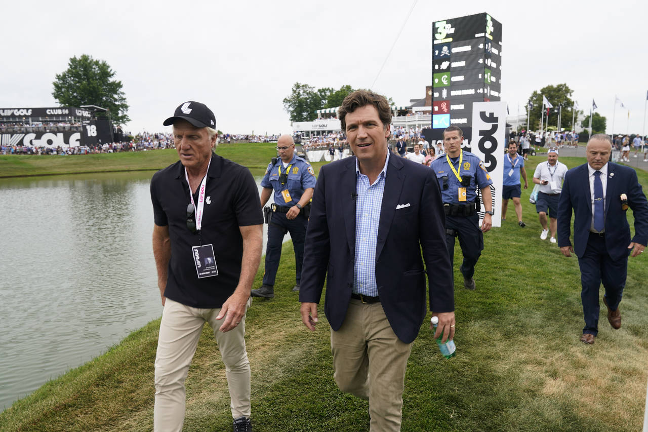 Tucker Carlson, front right, walks with LIV CEO Greg Norman, left, during the final round of the Be...