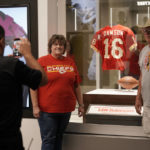 
              Fans have their photos made while standing next to the jersey of former Kansas City Chiefs quarterback Len Dawson before the start of an NFL preseason football game Thursday, Aug. 25, 2022, in Kansas City, Mo. Dawson, who helped the Kansas City Chiefs to their first Super Bowl title and is in the Pro Football Hall of Fame as a player and broadcaster, died Wednesday at the age of 87. (AP Photo/Charlie Riedel)
            