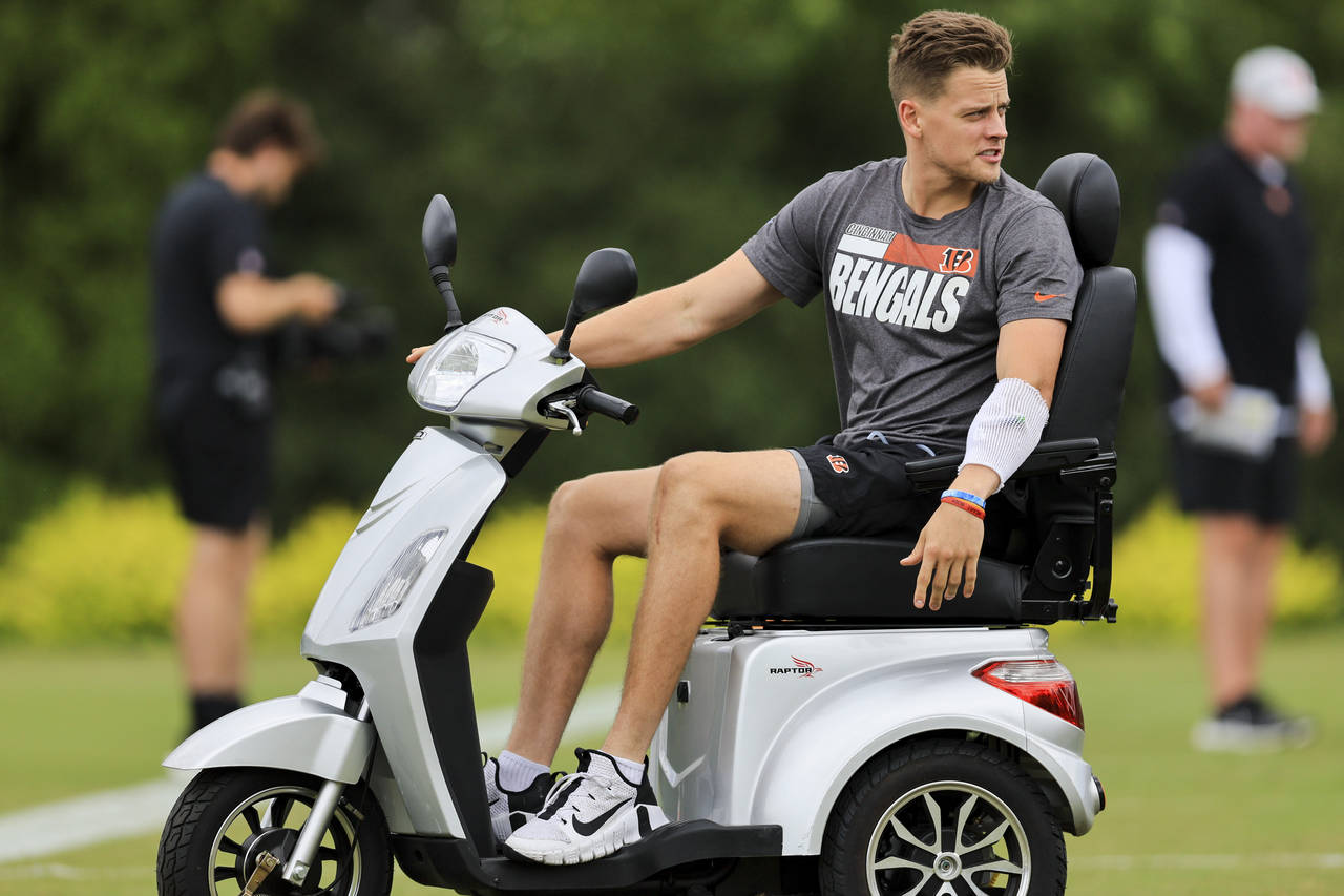 Cincinnati Bengals' Joe Burrow sits on a scooter as he watches during the NFL football team's train...