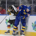 
              Sweden's Emil Andrae (4) is checked by Germany's Markus Schweiger (26) during the second period of an IIHF world junior hockey championships game Monday, Aug. 15, 2022, in Edmonton, Alberta. (Jason Franson/The Canadian Press via AP)
            