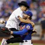 
              Musician Timmy Trumpet jumps into the arms of New York Mets' Tyler Naquin after throwing out a ceremonial first pitch before the Mets' baseball game against the Los Angeles Dodgers on Tuesday, Aug. 30, 2022, in New York. (AP Photo/Adam Hunger)
            