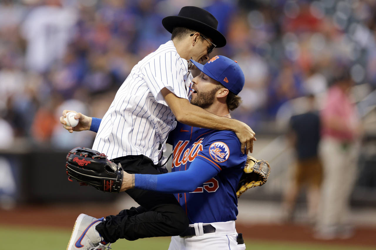Musician Timmy Trumpet jumps into the arms of New York Mets' Tyler Naquin after throwing out a cere...
