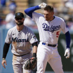 
              Los Angeles Dodgers' Freddie Freeman (5) gestures to the dugout after sliding safely into second base with a double next to Miami Marlins third baseman Jon Berti during the sixth inning of a baseball game Sunday, Aug. 21, 2022, in Los Angeles. (AP Photo/Marcio Jose Sanchez)
            