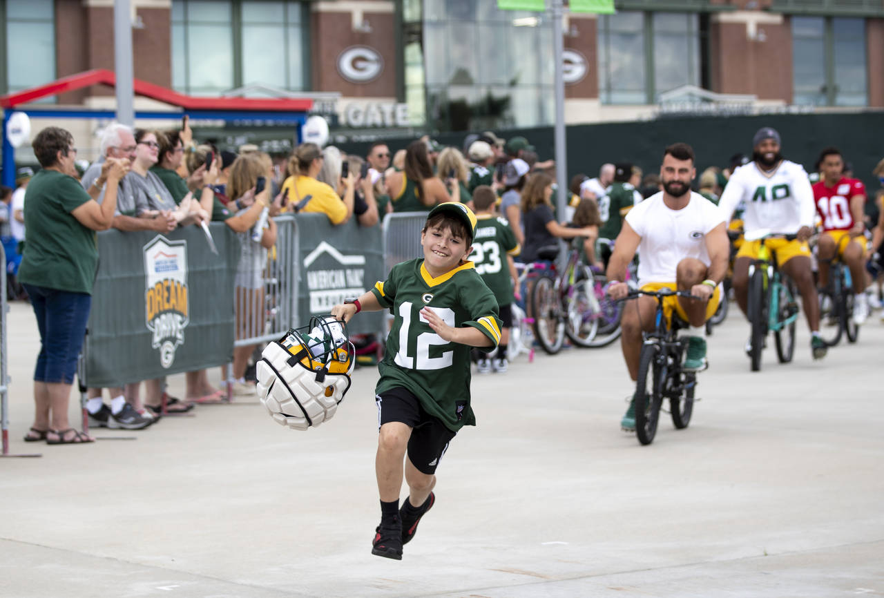 FILE - Green Bay Packers tight end Josiah Deguara, third from right, rides a young fan's bike as th...