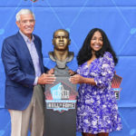 
              Melanie Mills, widow of former NFL player Sam Mills, right, and Jim Mora pose with his bust during an induction ceremony at the Pro Football Hall of Fame in Canton, Ohio, Saturday, Aug. 6, 2022. (AP Photo/David Dermer)
            