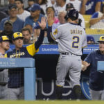 
              Milwaukee Brewers' Luis Urias (2) high-fives manager Craig Counsell, center left, after scoring off of a single hit by Jonathan Davis during the fifth inning of a baseball game against the Los Angeles Dodgers in Los Angeles, Tuesday, Aug. 23, 2022. (AP Photo/Ashley Landis)
            