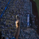 
              Angie Varella holds up a replica of a microphone at Dodger Stadium during a tribute held to honor late broadcaster Vin Scully before baseball game between the Los Angeles Dodgers and the San Diego Padres on Friday, Aug. 5, 2022, in Los Angeles. (AP Photo/Jae C. Hong)
            
