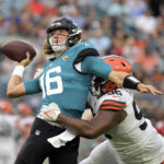 
              Jacksonville Jaguars quarterback Trevor Lawrence (16) throws a pass has he is hit by Cleveland Browns defensive tackle Jordan Elliott (96) during the first half of an NFL preseason football game, Friday, Aug. 12, 2022, in Jacksonville, Fla. (AP Photo/Phelan M. Ebenhack)
            
