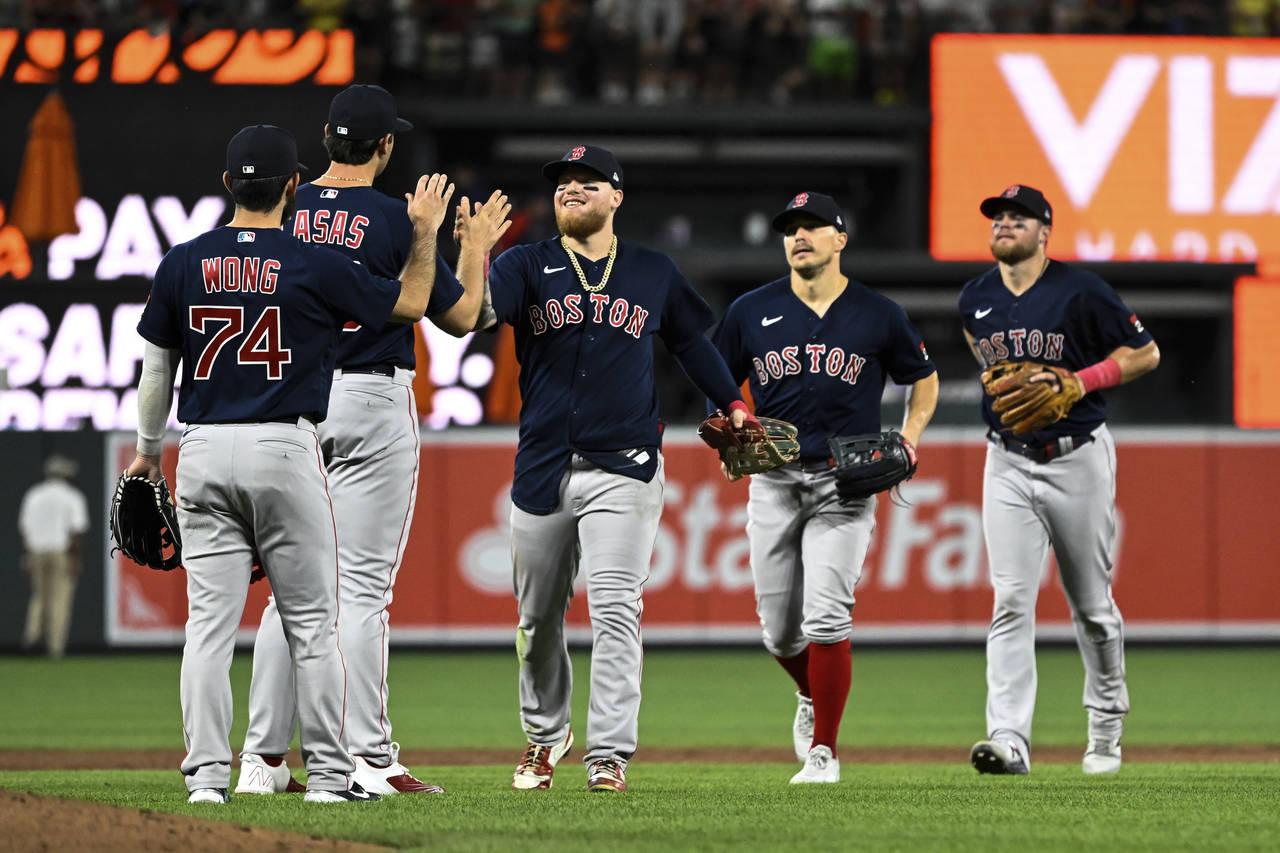 Boston Red Sox players greet each other after defeating the Baltimore Orioles 17-4 in a baseball ga...