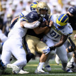 
              Delaware linebacker Anthony Toro, left, and defensive tackle Artis Hemmingway (91) try to bring down tackle Navy quarterback Tai Lavatai, center, during the first half of an NCAA college football game, Saturday, Sept. 3, 2022, in Annapolis, Md. (AP Photo/Nick Wass)
            