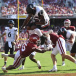 
              Cincinnati running back Corey Kiner (2) leaps over Arkansas defensive back Simeon Blair (15) to score a touchdown during the second half of an NCAA college football game Saturday, Sept. 3, 2022, in Fayetteville, Ark. (AP Photo/Michael Woods)
            