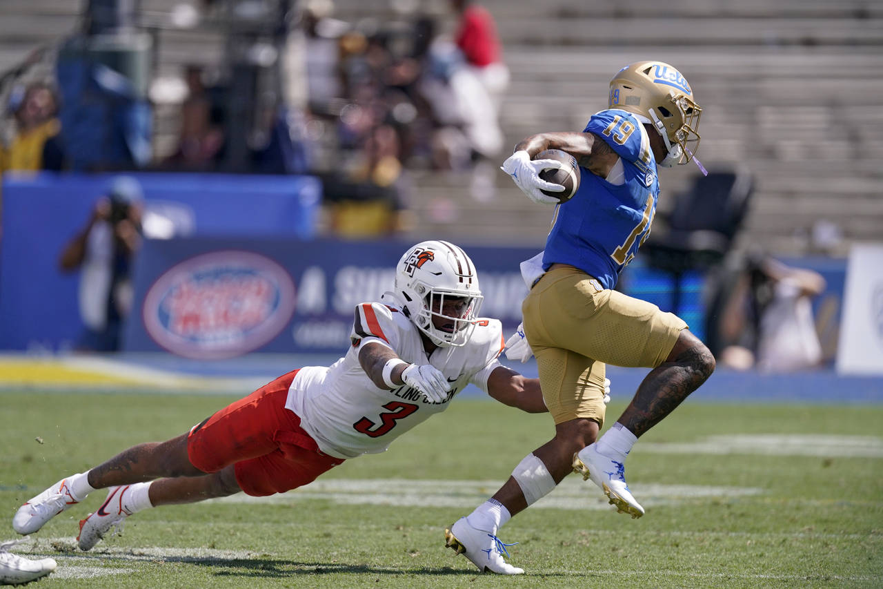 UCLA wide receiver Kazmeir Allen, right, runs the ball as Bowling Green safety Chris Bacon attempts...