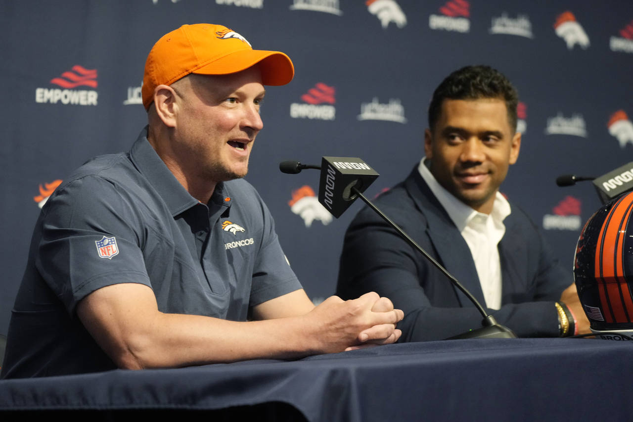 Denver Broncos quarterback Russell Wilson listens as coach Nathaniel Hackett responds to a question...