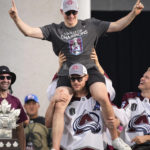 
              FILE  -Colorado Avalanche right wing Mikko Rantanen, center bottom, lifts defenseman Cale Makar, center top, during a rally outside the City/County Building for the NHL hockey champions after a parade through the streets of downtown Denver, Thursday, June 30, 2022. Looking on are center Nazem Kadri, left, and right wing Logan O'Connor. All the Stanley Cup parties and parades are over for the Colorado Avalanche. The shorter-than-most summer has run its fun-loving, Cup-hoisting course and training camp has arrived. It's time to get back to the task of defending the title. (AP Photo/David Zalubowski, File)
            