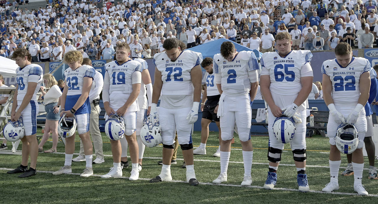 Members of the Indiana State NCAA college football team and fans observe a moment of silence for te...
