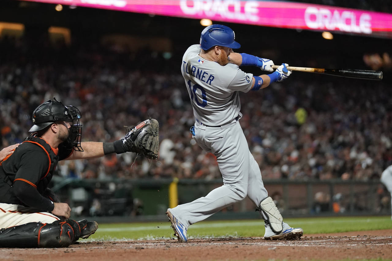 Los Angeles Dodgers designated hitter Justin Turner, right, hits an RBI single in front of San Fran...
