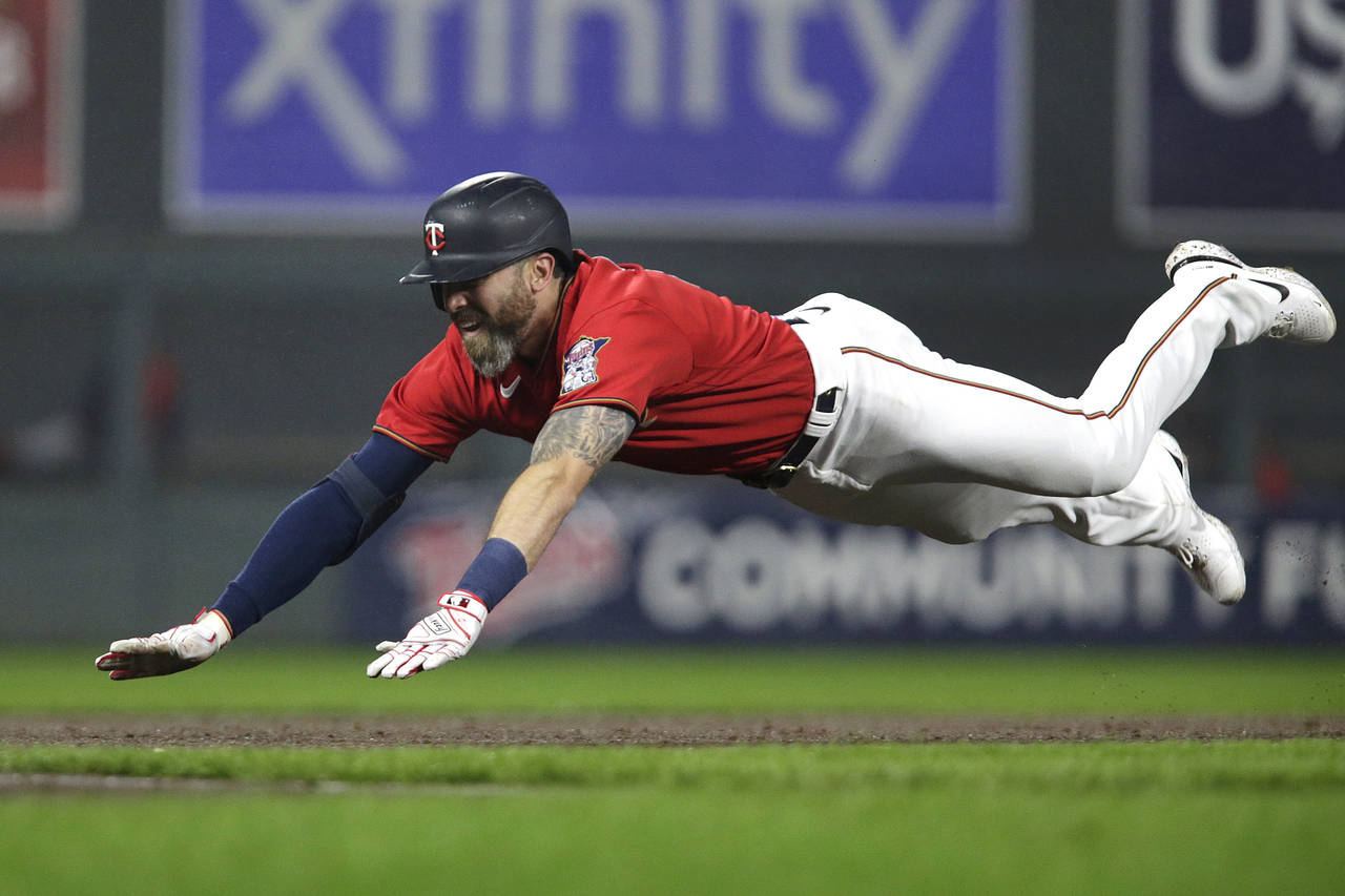 Minnesota Twins' Jake Cave dives into third base on a triple against the Los Angeles Angels during ...