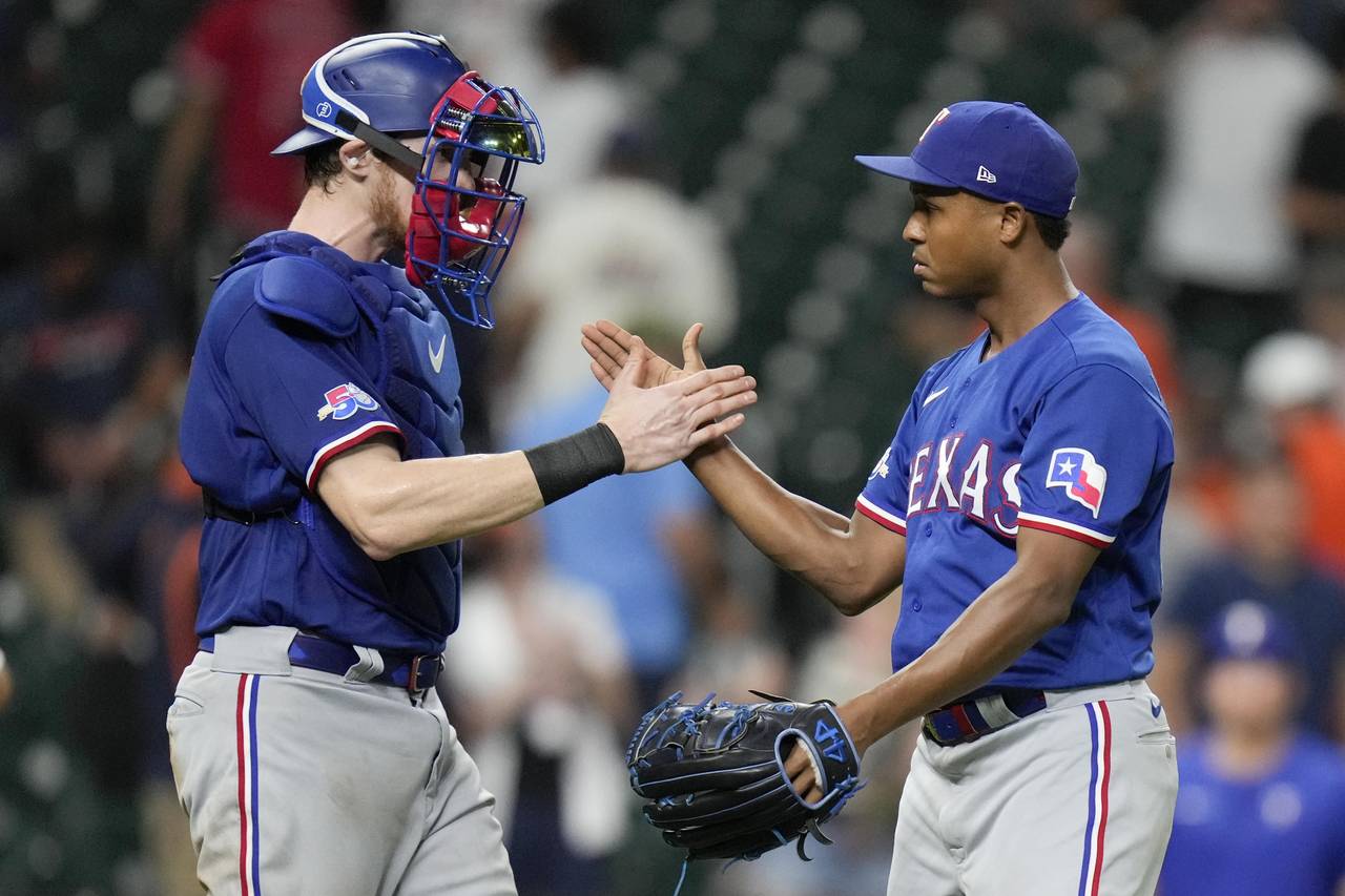 Texas Rangers relief pitcher Jose Leclerc, right, and catcher Sam Huff clasp hands after the team's...
