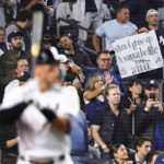 
              A fan holds a sign as New York Yankees designated hitter Aaron Judge prepares to bat against Boston Red Sox starting pitcher Brayan Bello during the first inning of a baseball game Sunday, Sept. 25, 2022, in New York. (AP Photo/Jessie Alcheh)
            