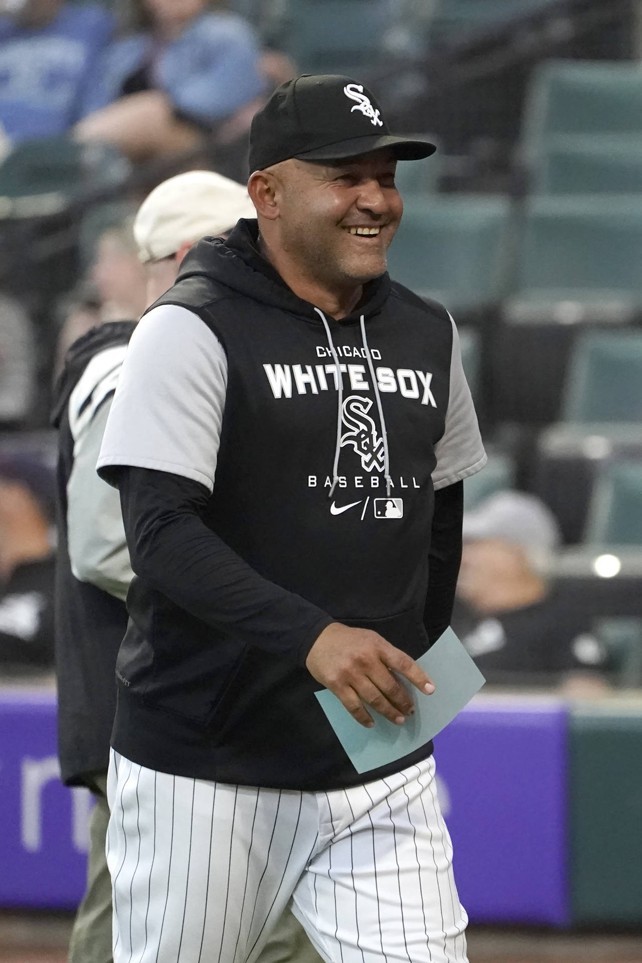 Chicago White Sox bench coach Miguel Cairo smiles as he returns to the dugout with the lineup card ...