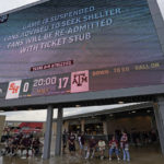 
              Fans sit under a scoreboard during a weather delay for an NCAA college football game between Sam Houston State and Texas A&M Saturday, Sept. 3, 2022, in College Station, Texas. (AP Photo/David J. Phillip)
            